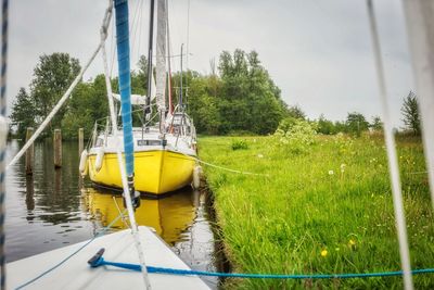 Sailboat moored in river against sky