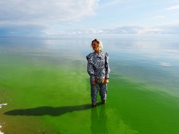 Full length of girl standing in sea against sky