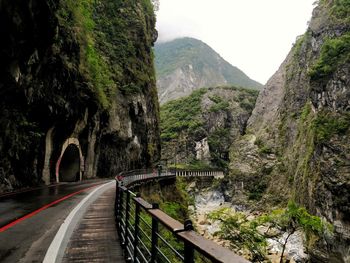 Road amidst trees and mountains against sky