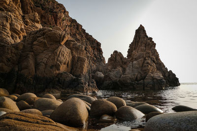 Rock formations in sea against clear sky