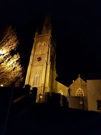 Low angle view of clock tower at night