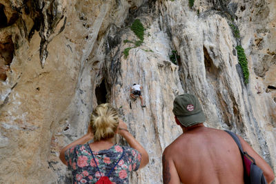 Rear view of people watching rock climbing at cliff