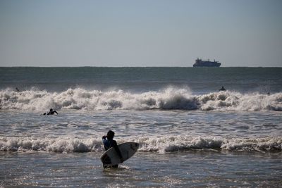 Rear view of a surfer walking on beach