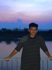 Portrait of young man standing against lake