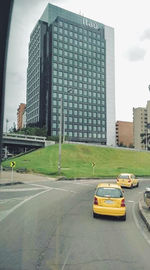 Cars on road by buildings against sky in city