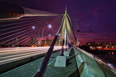 Light trails on bridge against sky at night