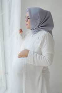 Portrait of young woman standing against wall