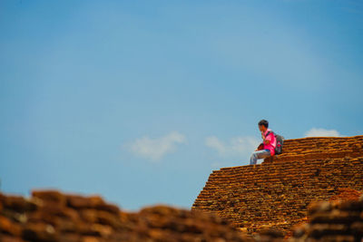 Low angle view of woman against blue sky