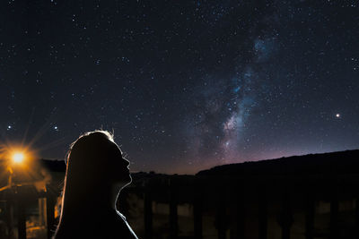 Silhouette woman standing against sky at night