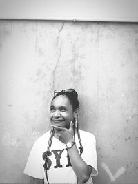Portrait of a smiling young woman standing against wall