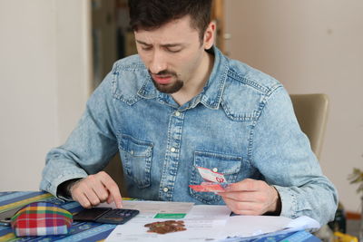 Young man looking away while sitting on table