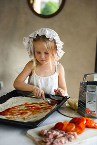 Little girl cooking pizza in the kitchen