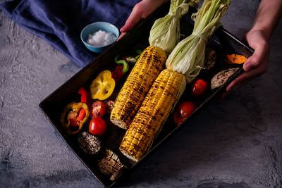 Cropped hands holding roasted vegetables in tray