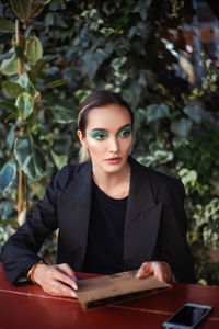 Young woman with fashionable bright makeup in a street cafe looks at the menu and makes an order