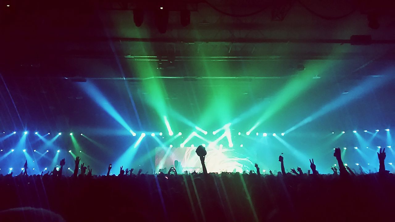 illuminated, night, large group of people, arts culture and entertainment, silhouette, enjoyment, event, lighting equipment, light - natural phenomenon, person, sky, crowd, lifestyles, blue, leisure activity, men, fun, performance, light