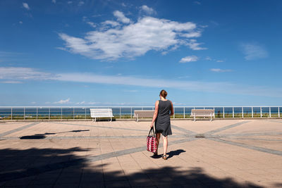 Rear view of woman walking on railing against sky