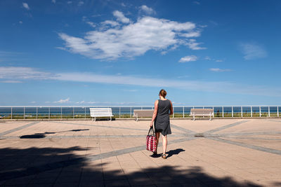 Rear view full length of woman walking at promenade on sunny day