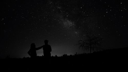 Low angle view of silhouette man standing on field against sky at night