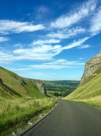 Road amidst field against sky