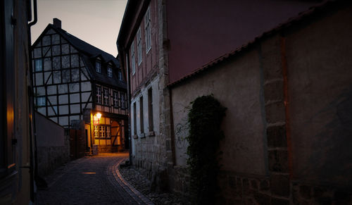 Illuminated street amidst buildings at night