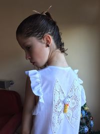 Rear view of girl with butterfly pattern on white dress at home