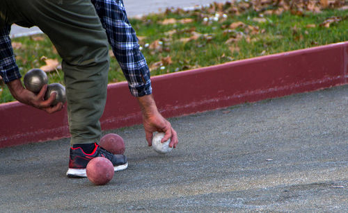 Low section of man holding petanque balls on footpath