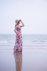 Woman standing on beach against sea against sky