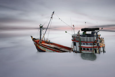 Fishing boat moored in sea against sky