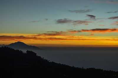 Scenic view of silhouette mountains against orange sky