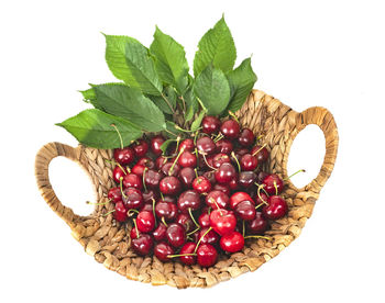 High angle view of cherries in wicker basket against white background