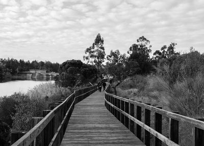 Pier on footbridge over lake against sky