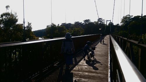 Rear view of people walking on footbridge