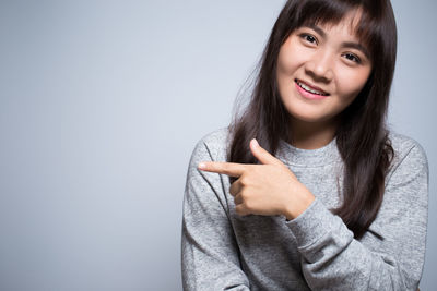 Smiling young woman against gray background