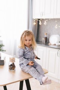 Cute girl sitting on table at home