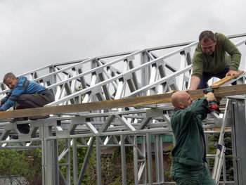 Manual workers making metallic built structure on field