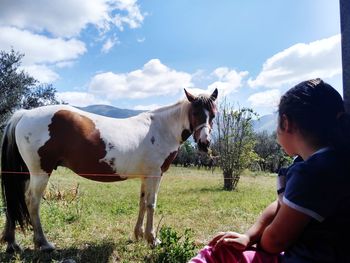 Side view of boy standing on field against sky