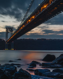 Suspension bridge over river against sky during sunset