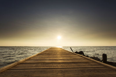 Pier over sea against sky during sunset