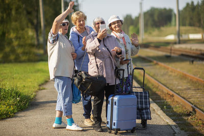 Group of senior women take a self-portrait on  platform waiting for  train  travel during a covid-19 