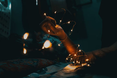 Cropped hand holding illuminated string light