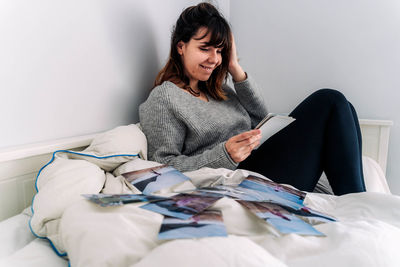 Young woman sitting on bed at home