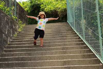 Girl with arms outstretched walking on steps