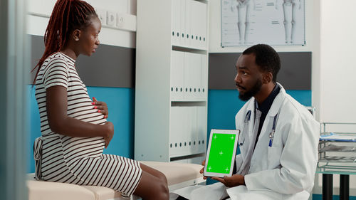 Doctor holding digital tablet while discussing with patient