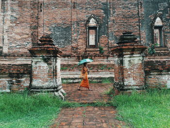 Rear view of woman standing against old building