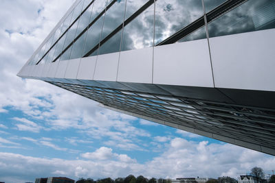 Low angle view of modern building against cloudy sky