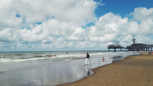 People at beach against cloudy sky