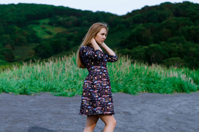 Young woman standing against plants