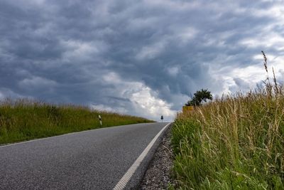 Surface level of road amidst field against sky