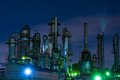 Low angle view of illuminated factory against sky at night
