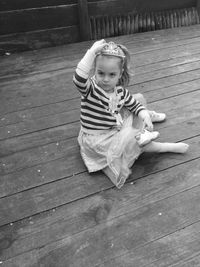 High angle portrait of cute girl wearing crown sitting on wooden floor